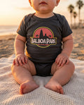 Baby wearing Balboa Park bodysuit on a San Diego beach at golden hour