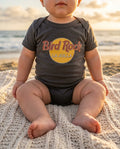 Baby wearing Bird Rock (Hard Rock Parody) bodysuit on a San Diego beach at golden hour