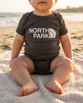 Baby wearing North Park (North Face Parody) bodysuit on a San Diego beach at golden hour