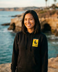 Person wearing La Jolla Ferrari Parody Hoodie in black at La Jolla Cove in San Diego