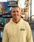 Person wearing Mission Beach Rollercoaster Hoodie - Unisex in yellow at North Park on University Avenue in San Diego