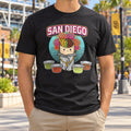 Man in a black San Diego Burrito City Connect T-shirt near a ballpark with Padres banners behind him